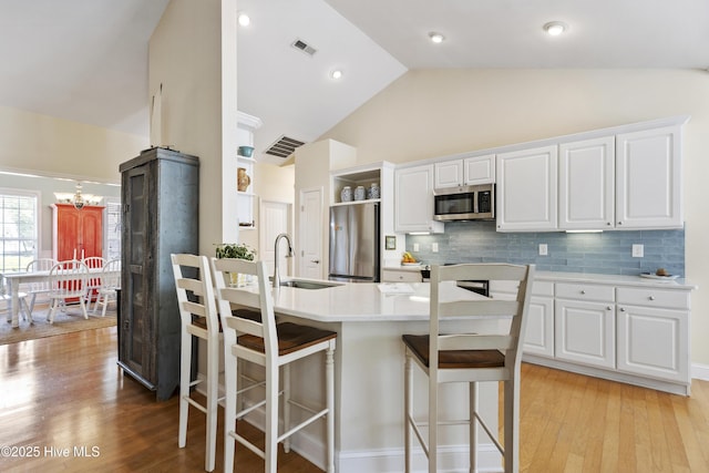 3733 Winstead Cir, Southport, NC 28461 - kitchen featuring a breakfast bar, a sink, light countertops, stainless steel appliances, and visible vents