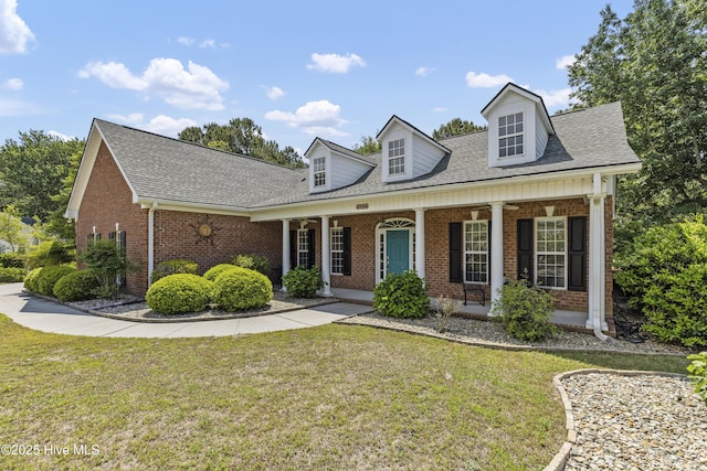 3733 Winstead Cir, Southport, NC 28461 - cape cod-style house with brick siding, a shingled roof, a front lawn, and a porch