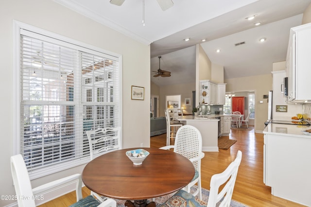 3733 Winstead Cir, Southport, NC 28461 - dining area with a ceiling fan, visible vents, crown molding, high vaulted ceiling, and light wood-style floors