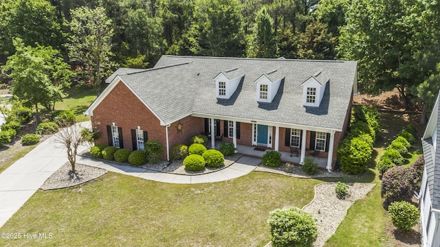 3733 Winstead Cir, Southport, NC 28461 - cape cod home featuring brick siding, a shingled roof, a front lawn, and covered porch