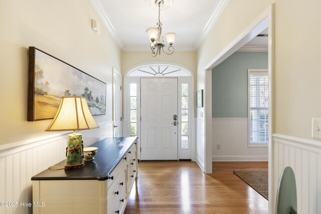 3733 Winstead Cir, Southport, NC 28461 - entryway with crown molding, an inviting chandelier, wood finished floors, and a wainscoted wall