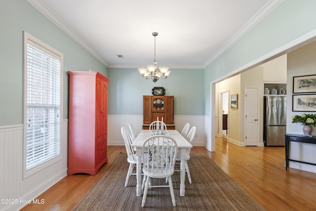 3733 Winstead Cir, Southport, NC 28461 - dining space with crown molding, a notable chandelier, a healthy amount of sunlight, and light wood finished floors