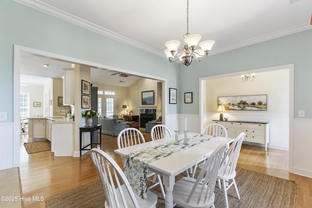 3733 Winstead Cir, Southport, NC 28461 - dining space with an inviting chandelier, a wainscoted wall, and light wood-style floors