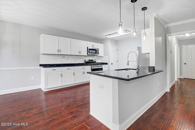 kitchen featuring stainless steel appliances, dark countertops, ornamental molding, and a sink