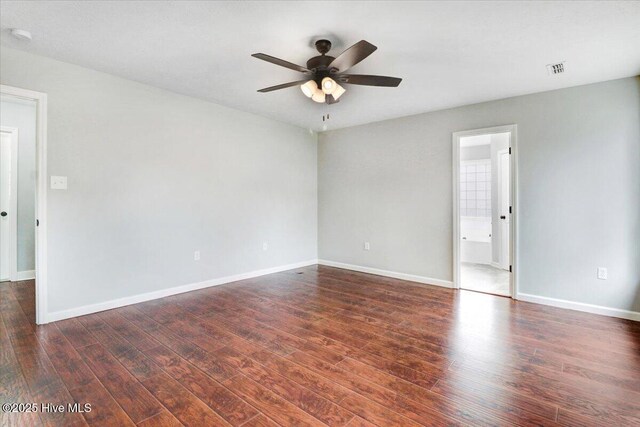 empty room featuring baseboards, visible vents, ceiling fan, and dark wood-type flooring