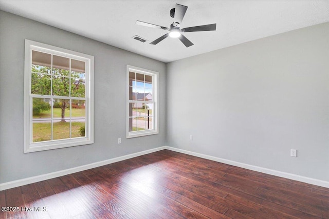 empty room with wood-type flooring, visible vents, a wealth of natural light, and baseboards