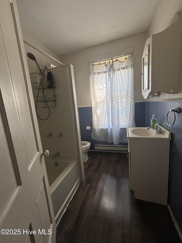 bathroom featuring baseboard heating, vanity, toilet, wood finished floors, and  shower combination