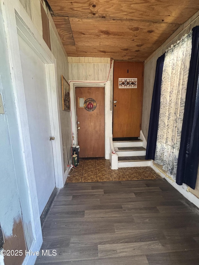 corridor with wooden walls, wooden ceiling, and wood finished floors