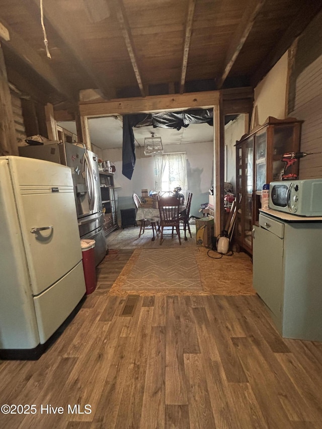 kitchen featuring fridge, stainless steel microwave, dark wood finished floors, and beam ceiling
