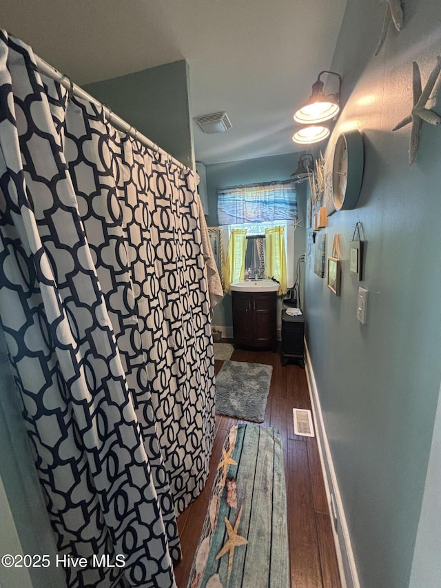 full bath featuring baseboards, visible vents, hardwood / wood-style flooring, and vanity