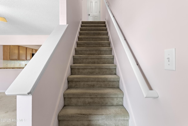 stairway featuring carpet floors and a textured ceiling