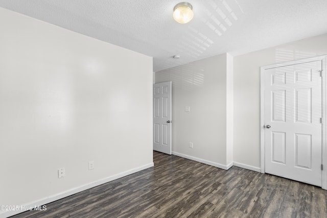 unfurnished bedroom featuring baseboards, dark wood-style floors, and a textured ceiling