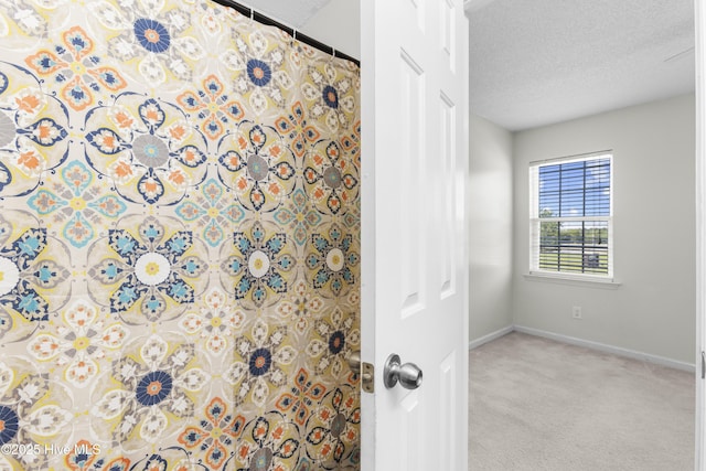 interior space featuring a textured ceiling, baseboards, and a shower with shower curtain