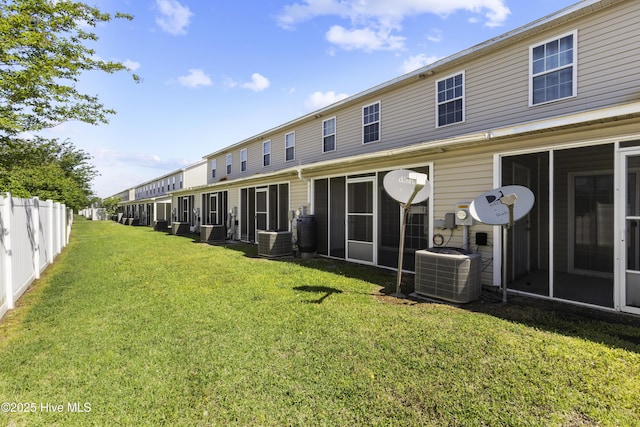 back of property with fence, central AC unit, and a yard