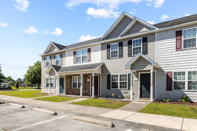 townhome / multi-family property featuring board and batten siding, uncovered parking, and a front lawn