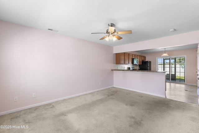 unfurnished living room with baseboards, a ceiling fan, visible vents, and light colored carpet