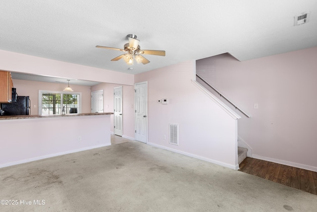 unfurnished living room with carpet, stairs, a ceiling fan, baseboards, and visible vents