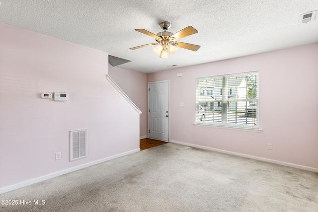 empty room featuring visible vents, carpet floors, baseboards, a textured ceiling, and a ceiling fan