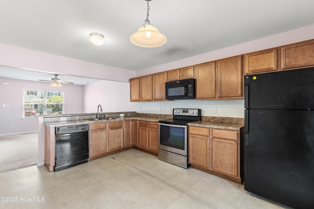 kitchen featuring a sink, a peninsula, black appliances, and brown cabinets