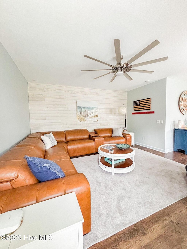 living room featuring a ceiling fan, wood walls, and wood finished floors