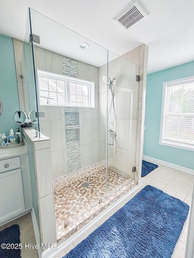bathroom featuring tile patterned floors, visible vents, a shower stall, and a wealth of natural light