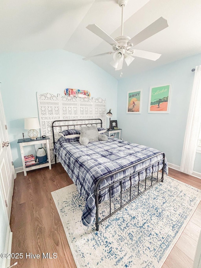 bedroom featuring baseboards, lofted ceiling, wood finished floors, and ceiling fan
