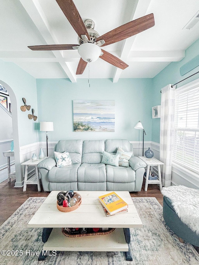 living area with ceiling fan, plenty of natural light, beam ceiling, and wood finished floors