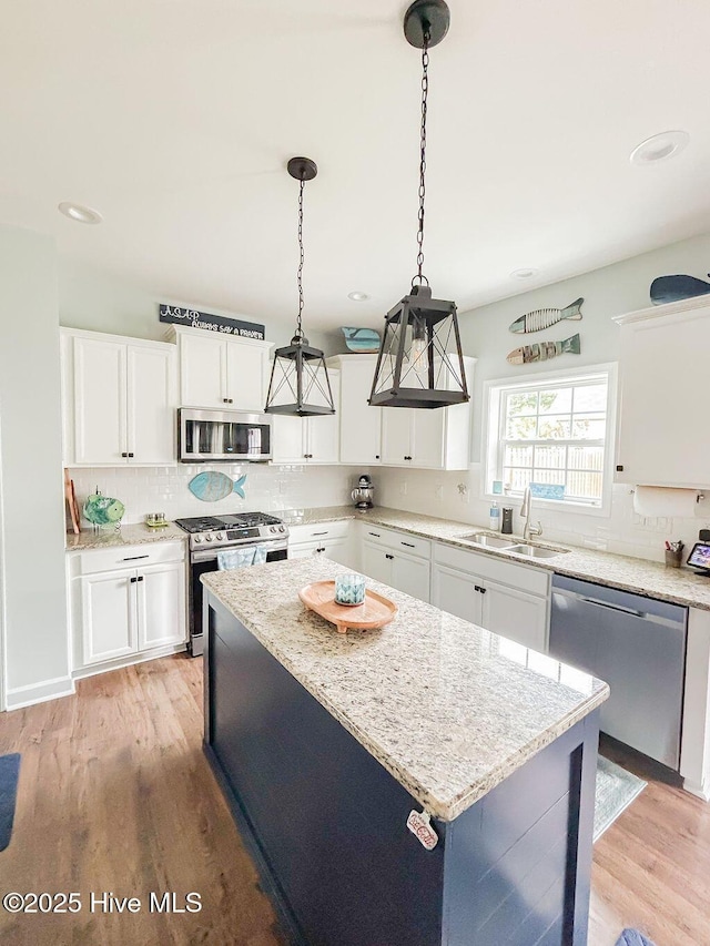 kitchen with decorative backsplash, appliances with stainless steel finishes, light stone countertops, a sink, and white cabinetry