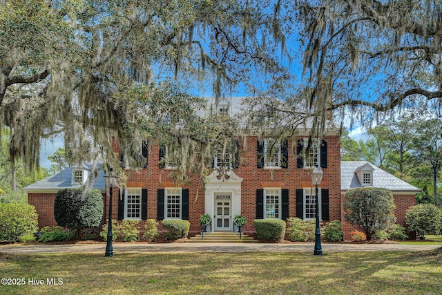colonial-style house featuring brick siding and a front yard