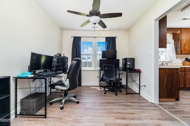office area featuring baseboards, a ceiling fan, light wood-type flooring, and visible vents