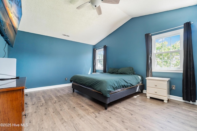 bedroom with visible vents, wood finished floors, baseboards, a ceiling fan, and vaulted ceiling