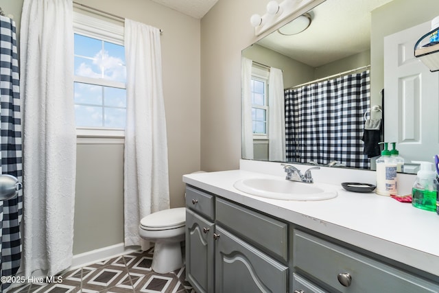 full bathroom featuring toilet, baseboards, and vanity