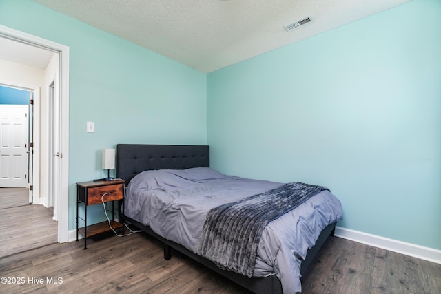 bedroom featuring baseboards, visible vents, and wood finished floors