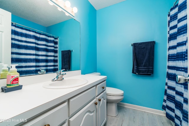 full bath with vanity, a textured ceiling, baseboards, and toilet