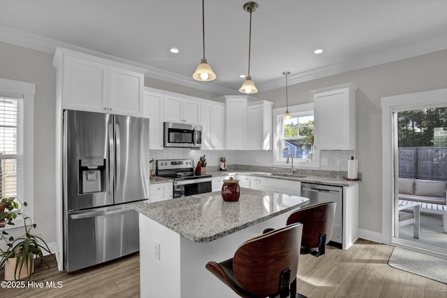 kitchen featuring light wood finished floors, stainless steel appliances, crown molding, white cabinetry, and backsplash