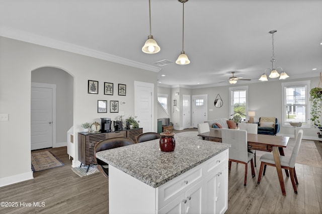 kitchen featuring light wood finished floors, crown molding, arched walkways, and recessed lighting