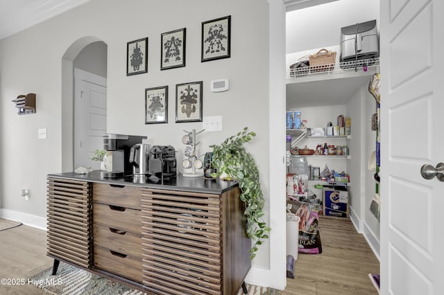 interior space with wood finished floors, baseboards, and arched walkways