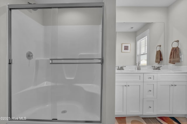 bathroom featuring double vanity, a stall shower, and a sink