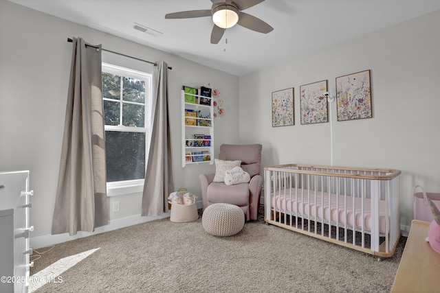 carpeted bedroom with baseboards, ceiling fan, visible vents, and a crib
