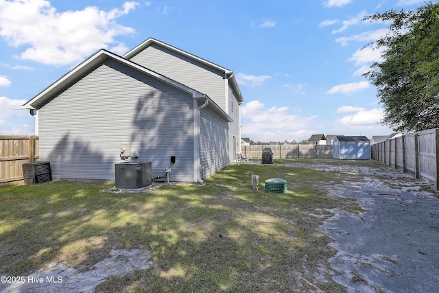 view of home's exterior with an outdoor structure, a fenced backyard, a storage unit, and central AC