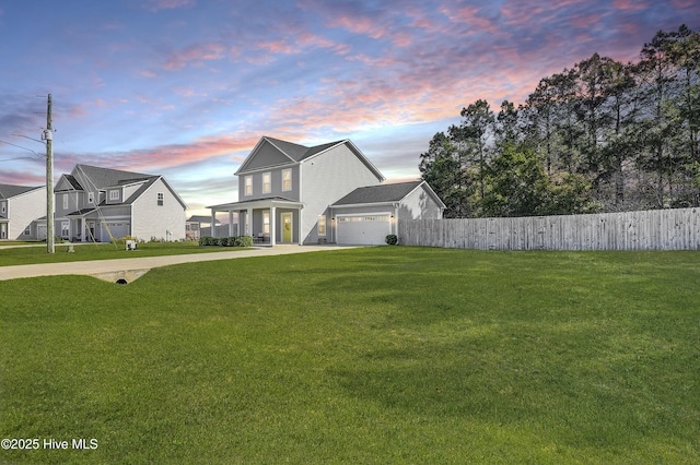 view of front facade featuring a yard, fence, a garage, and concrete driveway