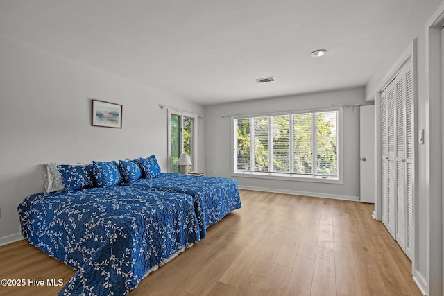 bedroom featuring visible vents, baseboards, and wood finished floors