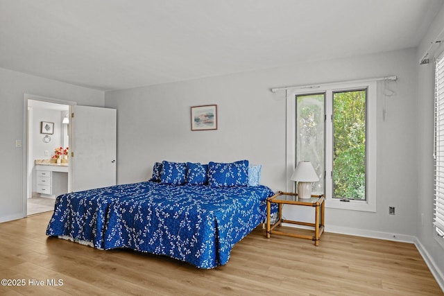 bedroom with baseboards, wood finished floors, and connected bathroom