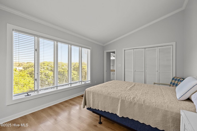 bedroom featuring crown molding, vaulted ceiling, wood finished floors, baseboards, and a closet