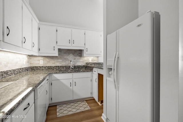 kitchen featuring white cabinets, a sink, white appliances, wood finished floors, and tasteful backsplash