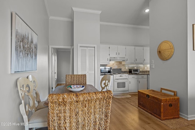 kitchen featuring white gas range, white cabinets, stainless steel microwave, ornamental molding, and under cabinet range hood