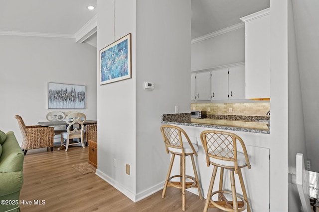 289 Salter Path Rd Unit 32, Pine Knoll Shores, NC 28512 - bar with crown molding, baseboards, tasteful backsplash, light wood finished floors, and bar area