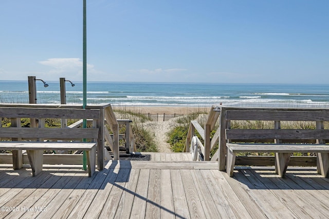 view of home's community with a deck with water view and a beach view