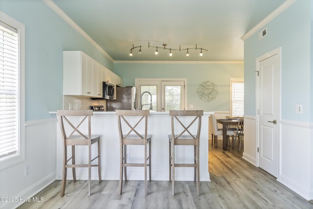 615 N New River Dr Unit E, Surf City, NC 28445 - kitchen featuring a kitchen bar, appliances with stainless steel finishes, white cabinets, a peninsula, and light wood-style flooring
