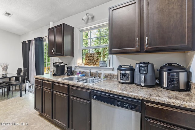 kitchen featuring light tile patterned floors, stainless steel dishwasher, dark brown cabinets, and visible vents